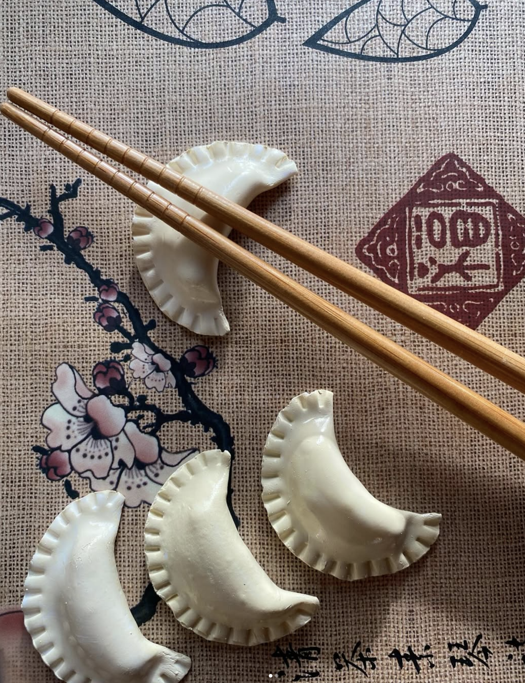 Handmade ceramic decorative pieces in the shape of dumplings, arranged on a patterned surface