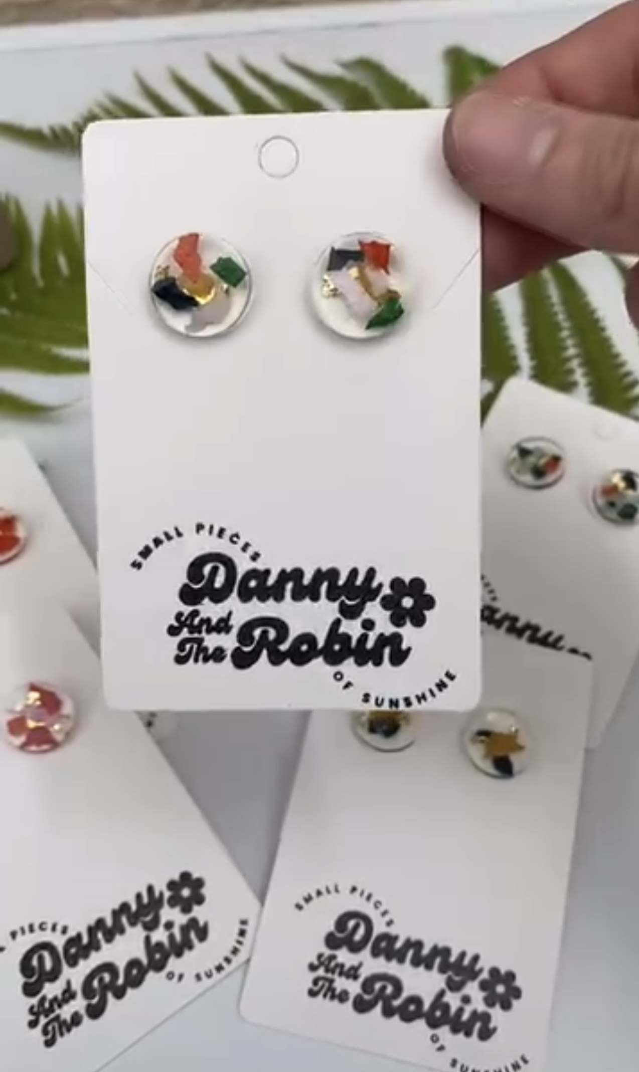 Clear resin stud earrings with abstract colourful patterns on Danny And The Robin branded jewellery cards
